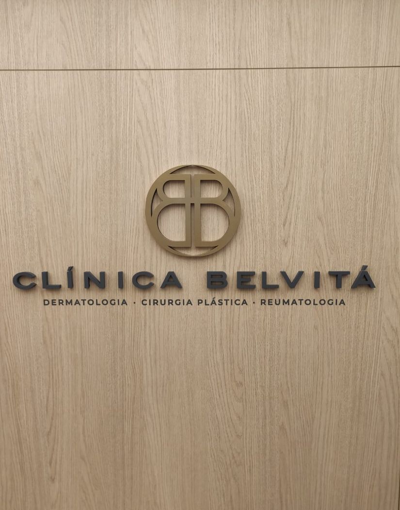 Logotipo Clínica Belvitá em acrílico dourado sobre painel de madeira